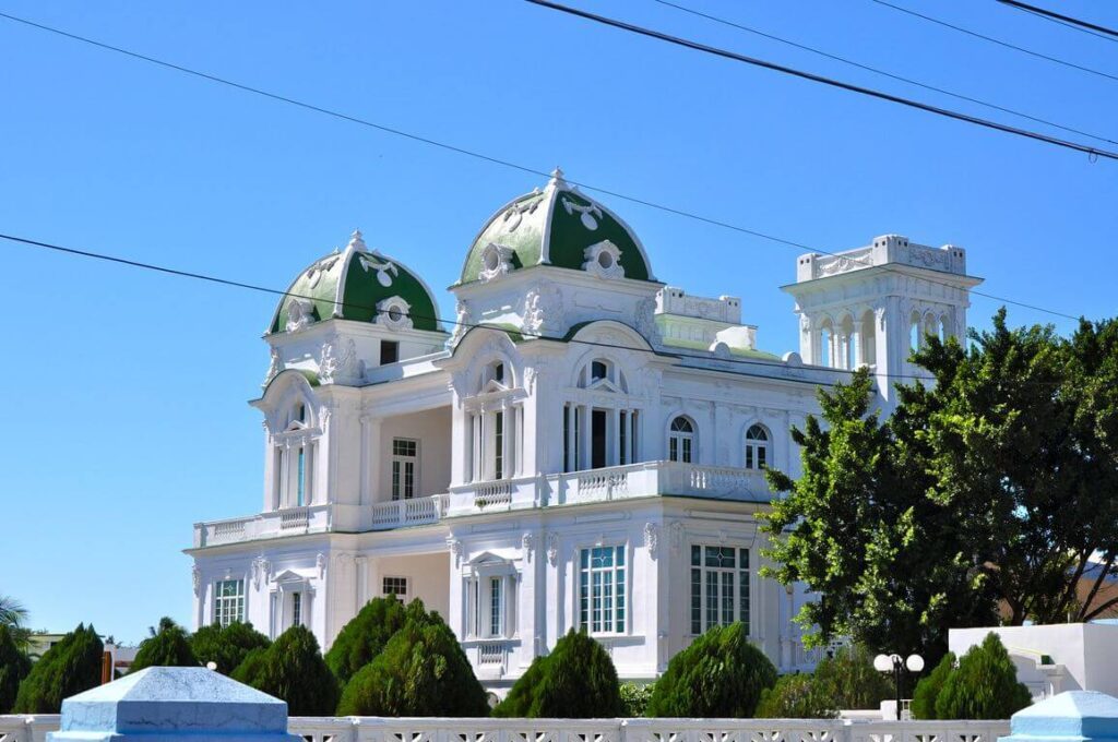Palais blanc aux dômes verts et tourelles ornées, entouré d'arbres à Cienfuegos, Cuba