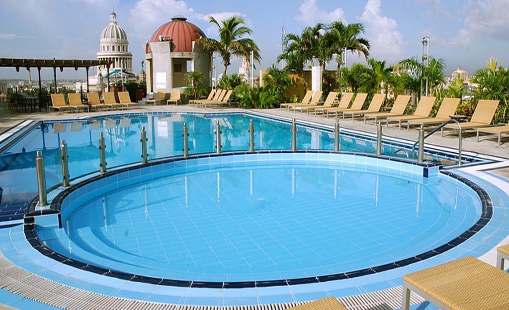 Piscine sur toit-terrasse d'hôtel avec transats et vue sur le Capitole de La Havane, Cuba