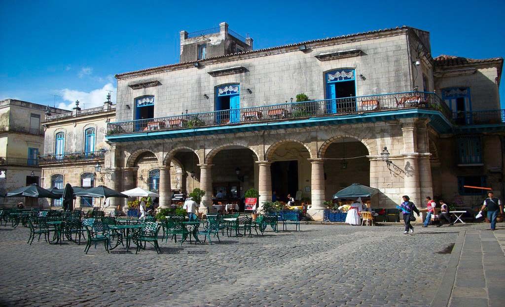 Place pavée de La Havane avec bâtiment colonial à arcades, terrasses et passants