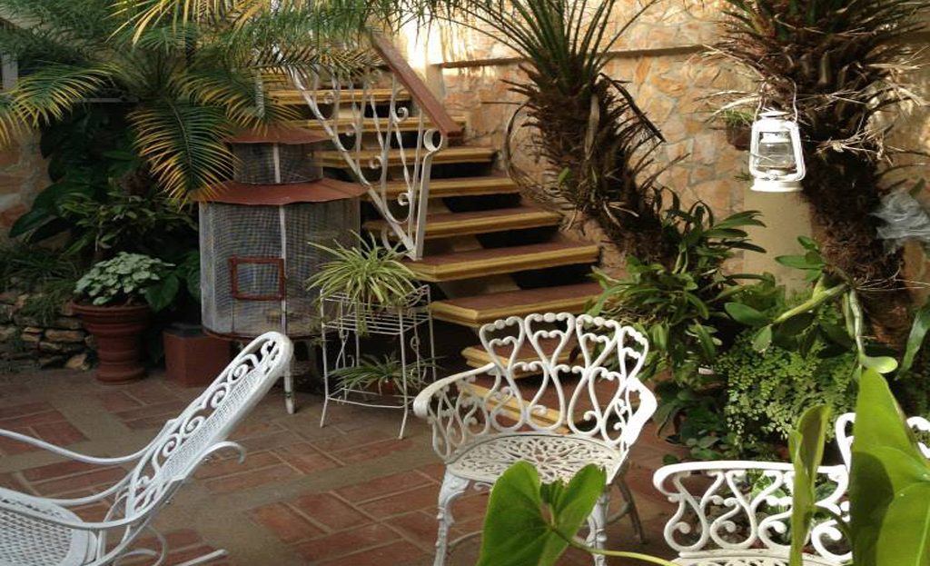Patio intérieur cubain avec chaises en fer forgé blanc, escalier et plantes tropicales, Remedios