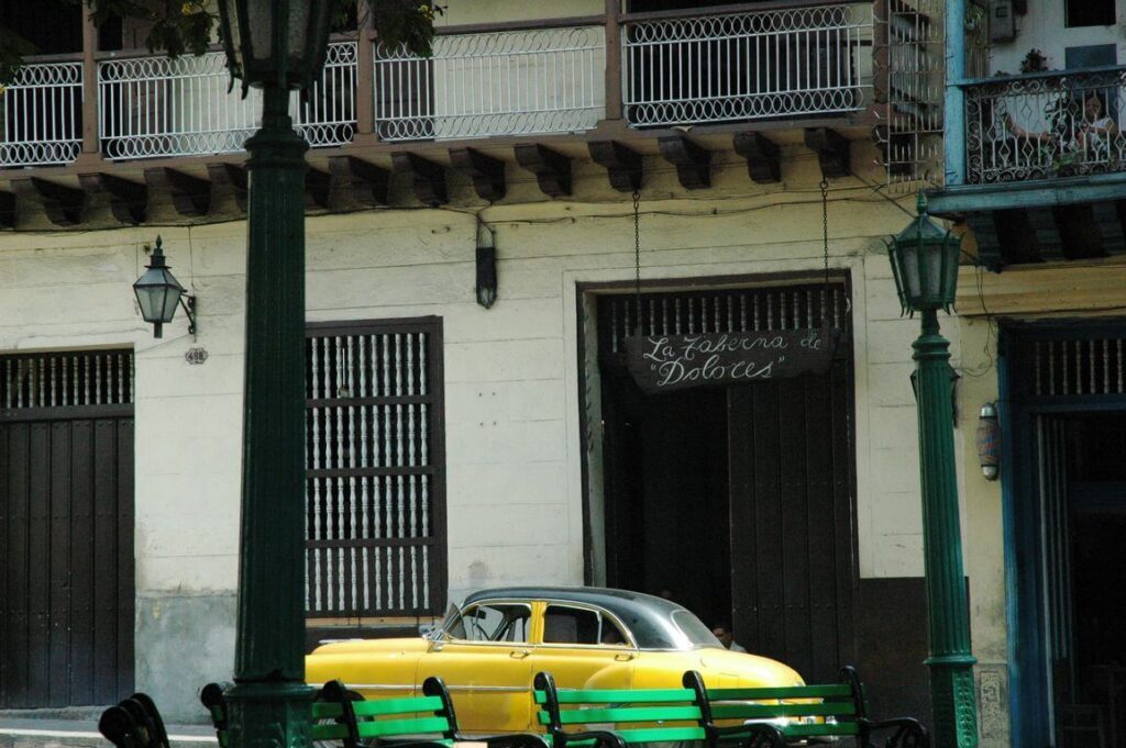 Voiture américaine jaune vintage devant "La Taberna de Dolores", façade coloniale à Santiago de Cuba