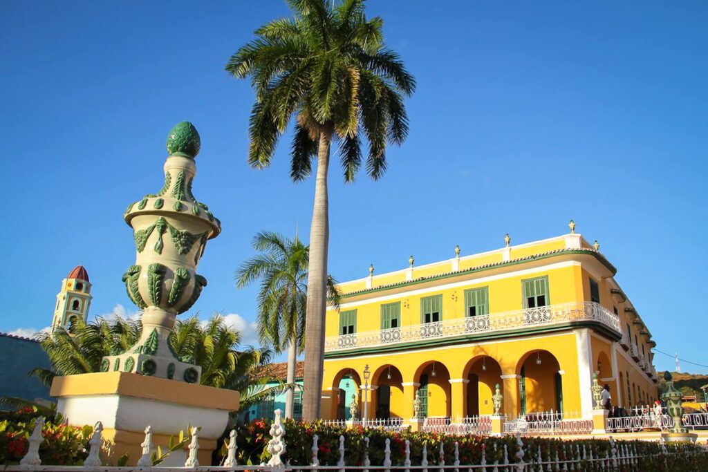 Bâtiment colonial jaune à balcon blanc et palmiers sur la place principale de Trinidad, Cuba