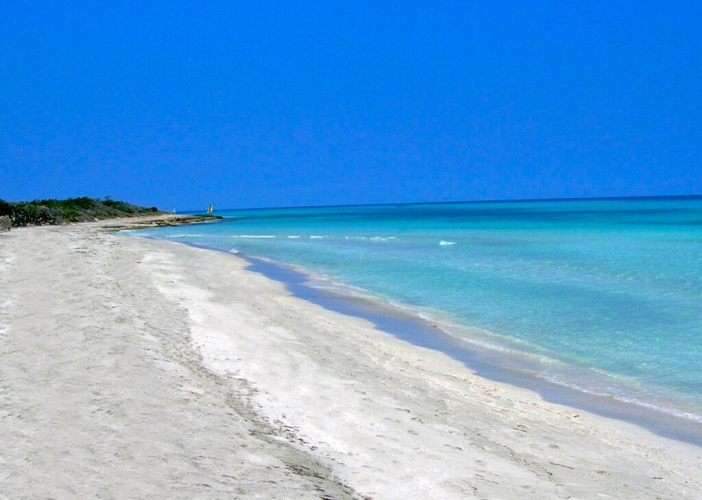 Plage de sable blanc et eau turquoise à Varadero, Cuba, avec petits voiliers au loin