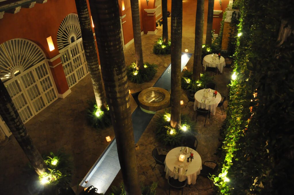 Cour intérieure d'hôtel avec tables dressées, palmiers et fontaine, Carthagène, Colombie, vue de nuit