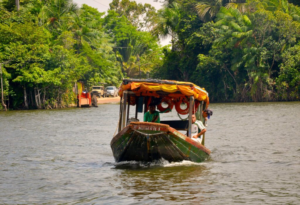 Bateau en bois avec toit orange transportant des passagers sur une rivière brésilienne bordée de végétation