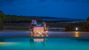 Couple dînant en soirée au bord d'une piscine éclairée aux bougies