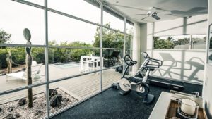 Salle de sport moderne avec baie vitrée donnant sur piscine et jardin