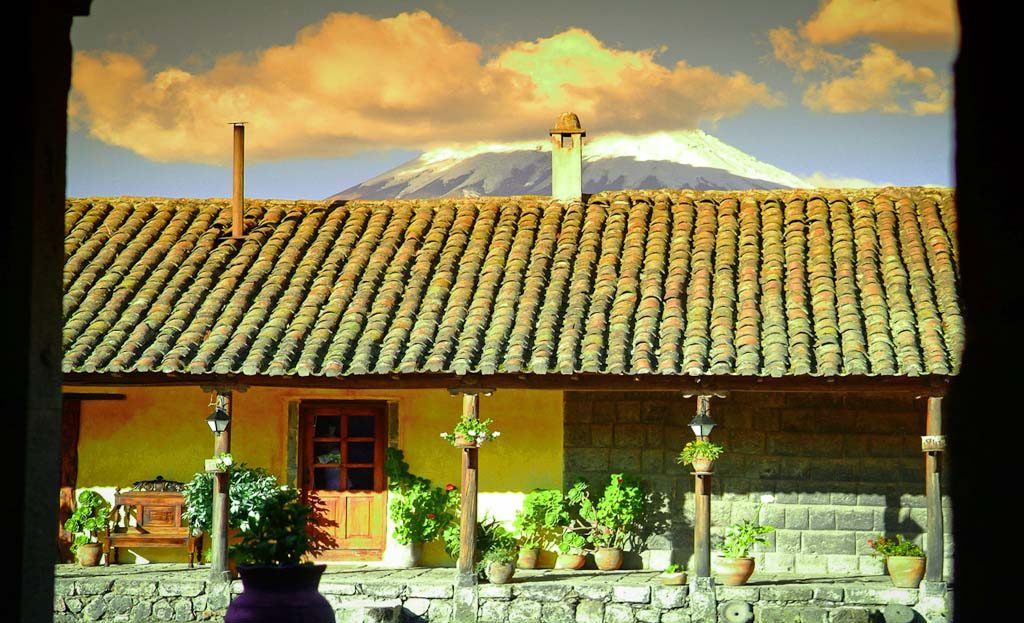 Toit de tuiles d'une hacienda équatorienne avec volcan enneigé en arrière-plan, près de Quito