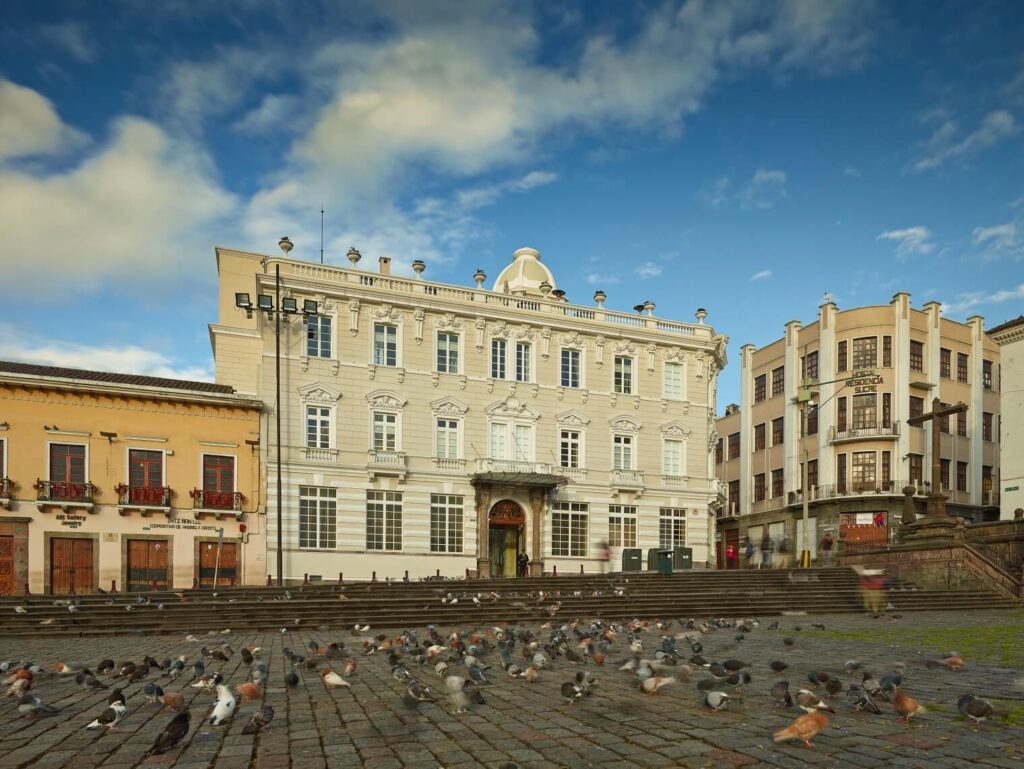 Place pavée de Quito avec pigeons au sol devant des bâtiments coloniaux historiques