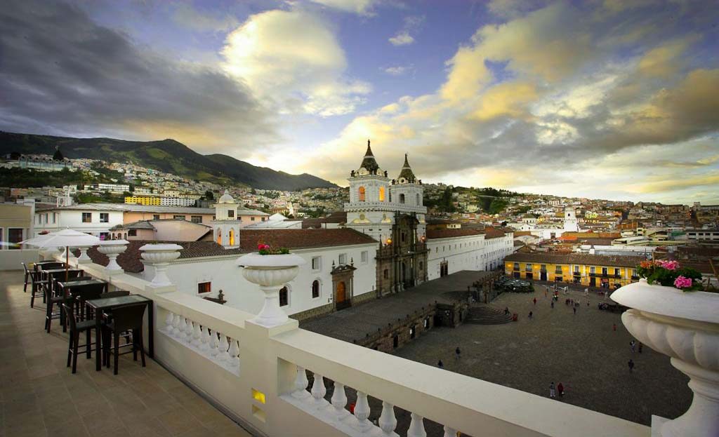 Vue depuis une terrasse à Quito surplombant une place et une église coloniale, montagnes en arrière-plan, Equateur