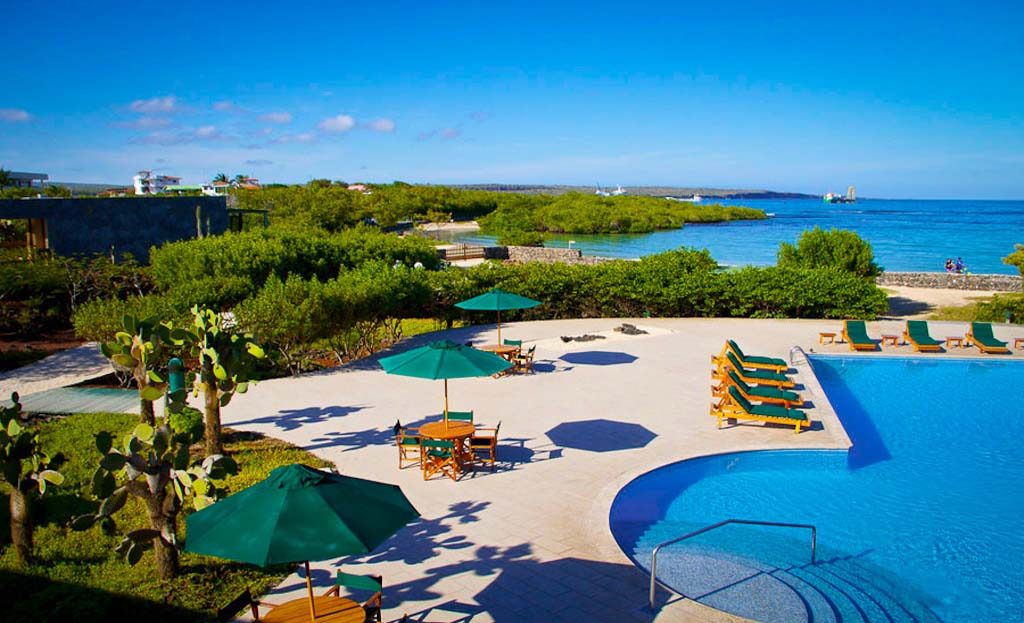 Piscine d'hôtel avec transats et parasols face à l'océan aux îles Galapagos
