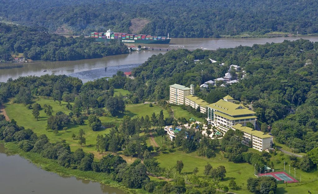 Vue aérienne d'un hôtel entouré de forêt tropicale près du canal de Panama avec cargo
