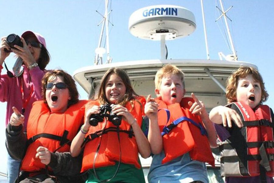 Enfants en gilets de sauvetage pointant du doigt vers la mer depuis un bateau, île de Saboga, Panama