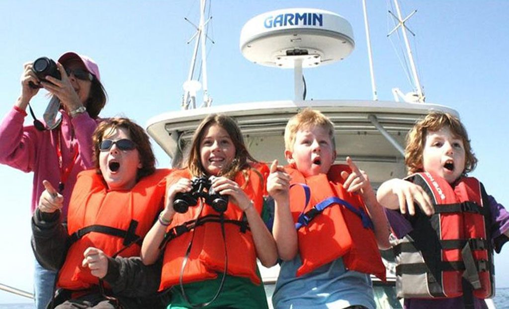 Enfants en gilets de sauvetage pointant du doigt vers la mer depuis un bateau, île de Saboga, Panama