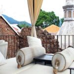Terrasse avec canapés et coussins face aux toits d'Antigua et un volcan, Guatemala
