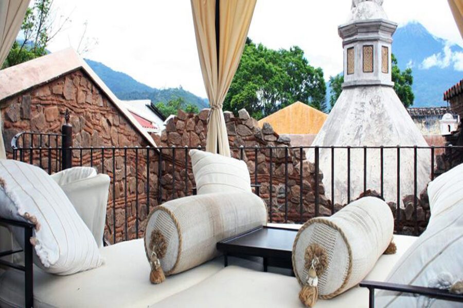 Terrasse avec canapés et coussins face aux toits d'Antigua et un volcan, Guatemala