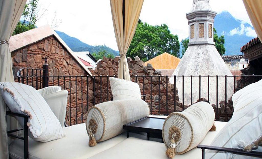 Terrasse avec canapés et coussins face aux toits d'Antigua et un volcan, Guatemala