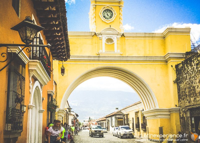 Arche jaune de Santa Catalina avec horloge surplombant une rue pavée à Antigua Guatemala