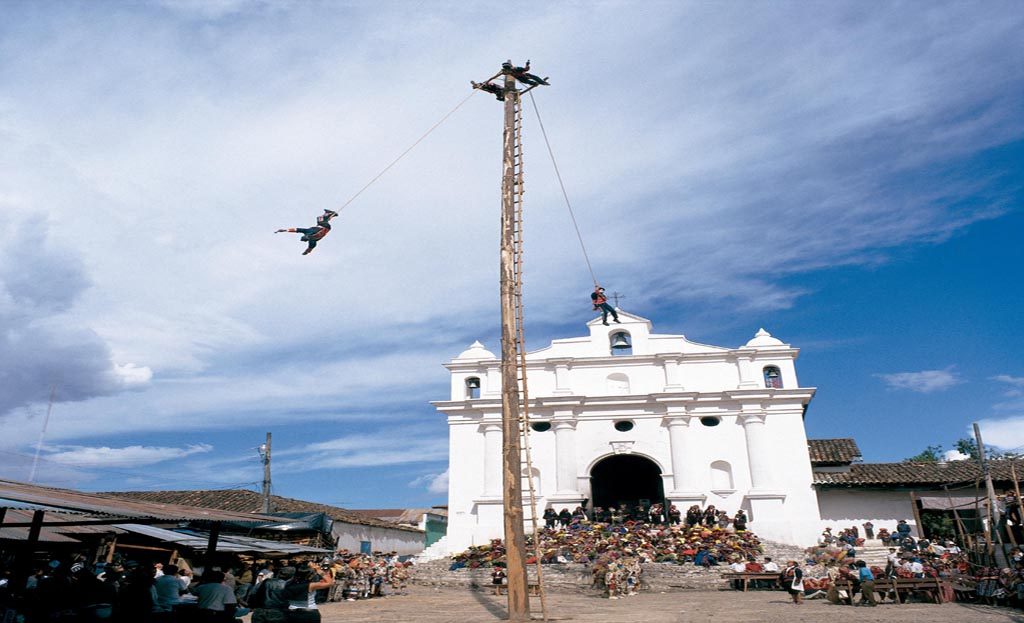 Voladores suspendus à des cordes tournant autour d'un mât devant l'église de Chichicastenango, Guatemala