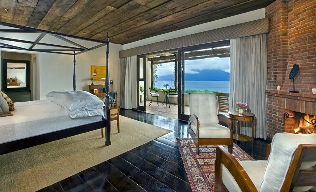 Chambre d'hôtel avec lit à baldaquin, cheminée en brique et vue sur le lac Atitlan