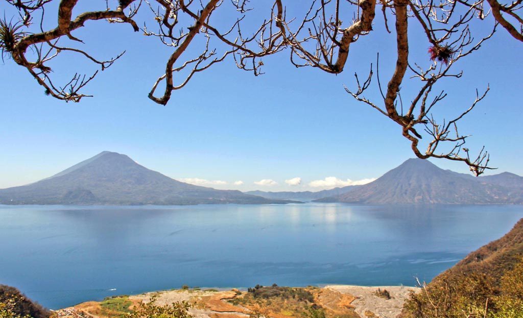 Vue du lac Atitlan encadrée par des branches, volcans en arrière-plan, Guatemala