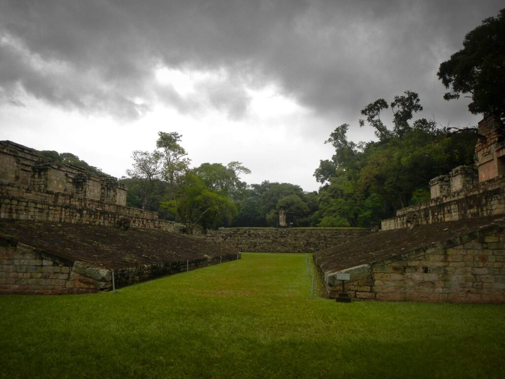 Terrain de jeu de balle maya de Copán, gradins en pierre et pelouse sous ciel nuageux, Honduras