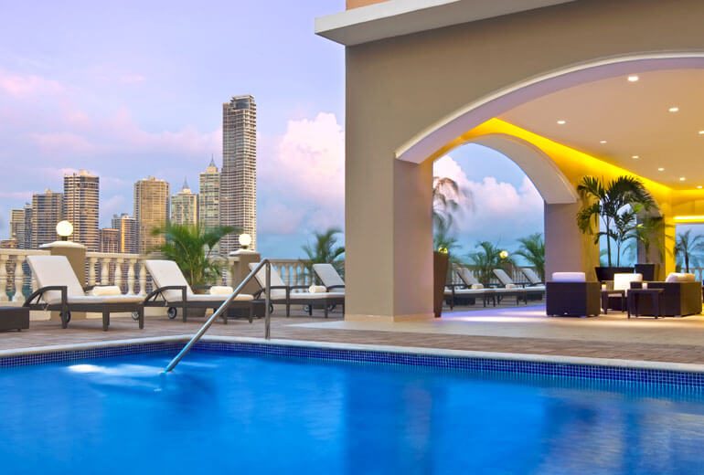 Piscine d'hôtel en terrasse avec vue sur les gratte-ciel de Panama City au crépuscule