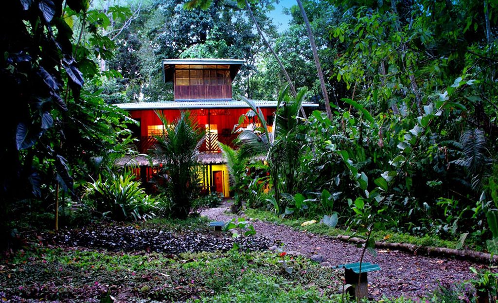 Maison rouge illuminée entourée d'une végétation tropicale dense, côte Caraïbe du Costa Rica