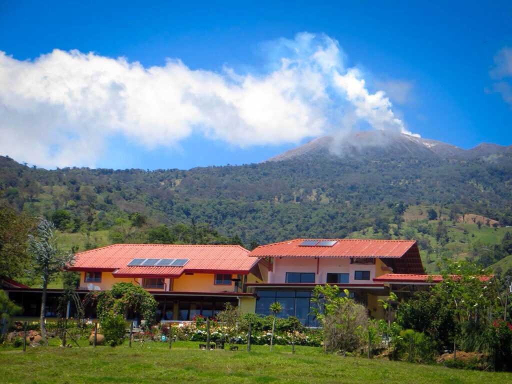 Hôtel à toits rouges avec panneaux solaires face au volcan Turrialba fumant, Costa Rica