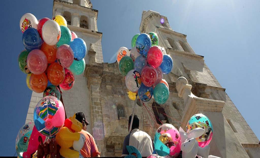 Ballons colorés vendus devant une église coloniale à Campeche, Mexique