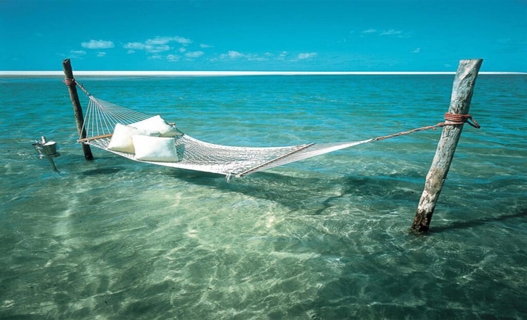 Hamac blanc suspendu au-dessus des eaux turquoise transparentes, île d'Holbox, Mexique