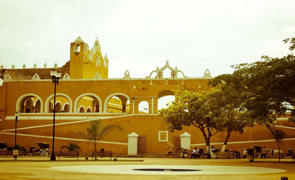 Convento franciscain jaune à arcades avec calèches sur la place d'Izamal, Yucatán, Mexique