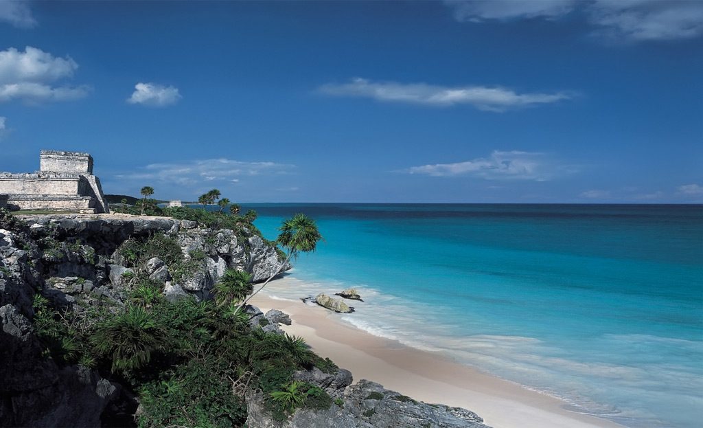 Ruines mayas sur falaise rocheuse surplombant une plage et mer turquoise à Tulum