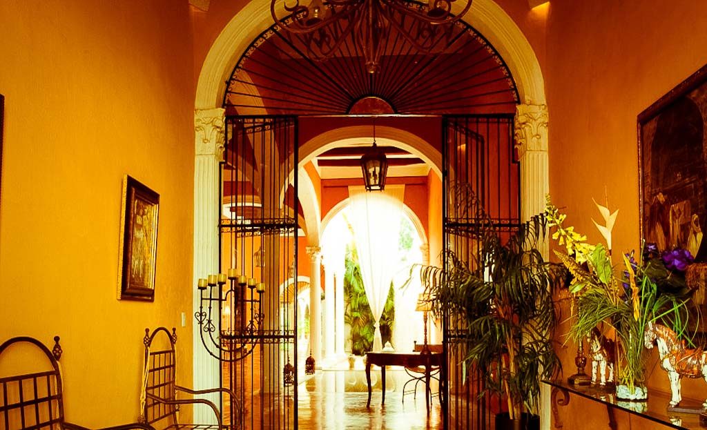 Entrée voûtée d'une hacienda coloniale au Yucatán, portails en fer forgé et décoration intérieure ornée