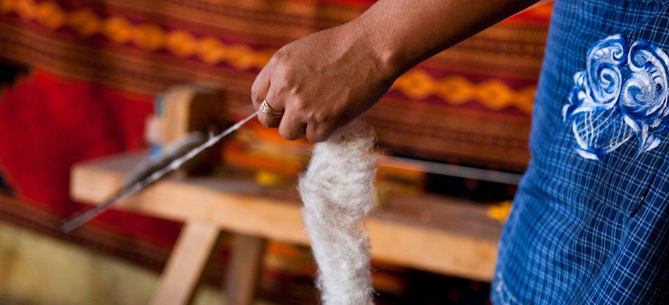 Artisan filant la laine à la main devant un métier à tisser traditionnel à Oaxaca, Mexique