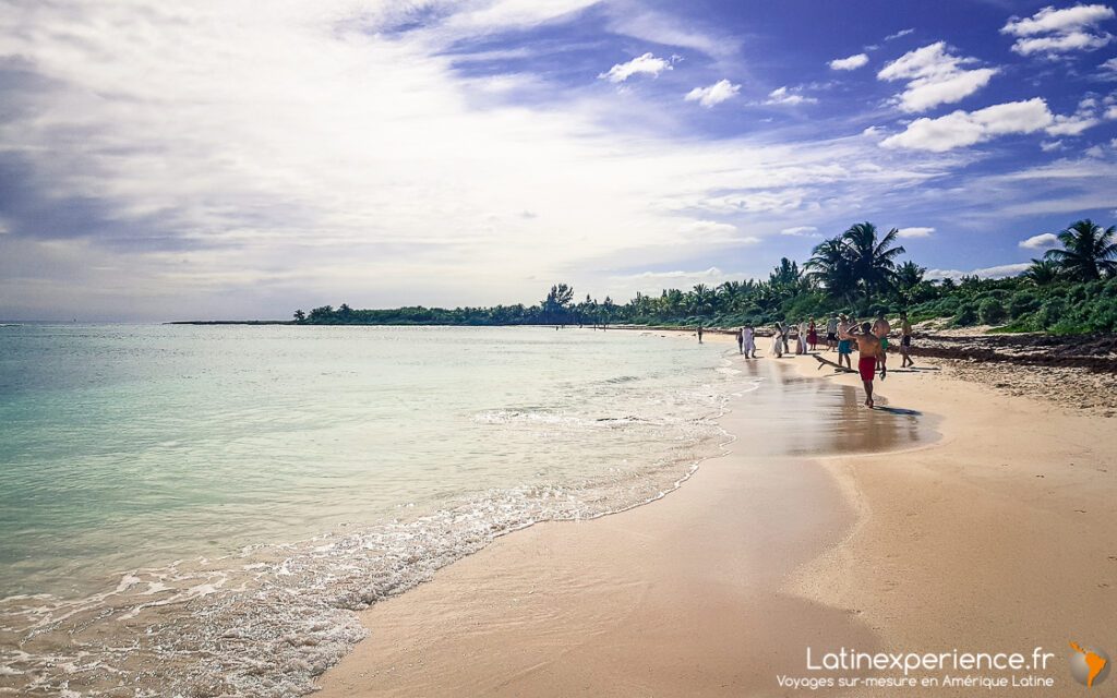 Plage de sable blanc et mer turquoise avec promeneurs, littoral près de Playa del Carmen au Mexique