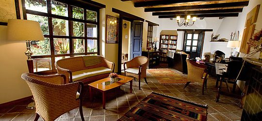 Salon d'hôtel avec canapé en rotin, cheminée et bibliothèque à San Cristobal de las Casas, Mexique