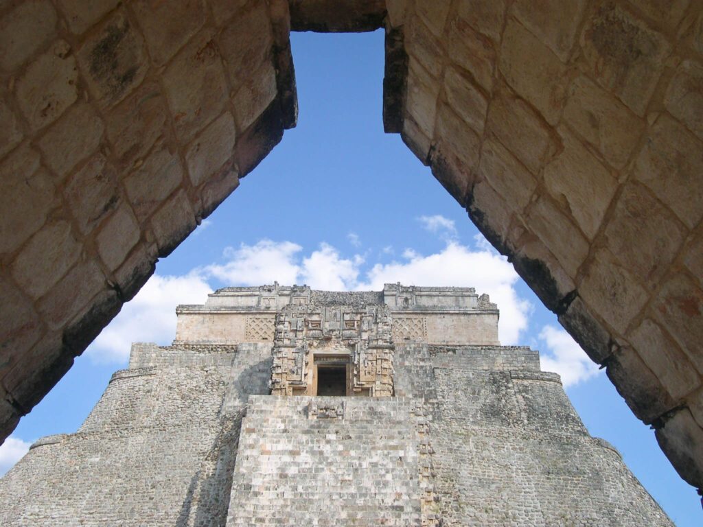 Vue en contre-plongée de la pyramide du Devin à Uxmal, Mexique, cadrée par une arche en pierre