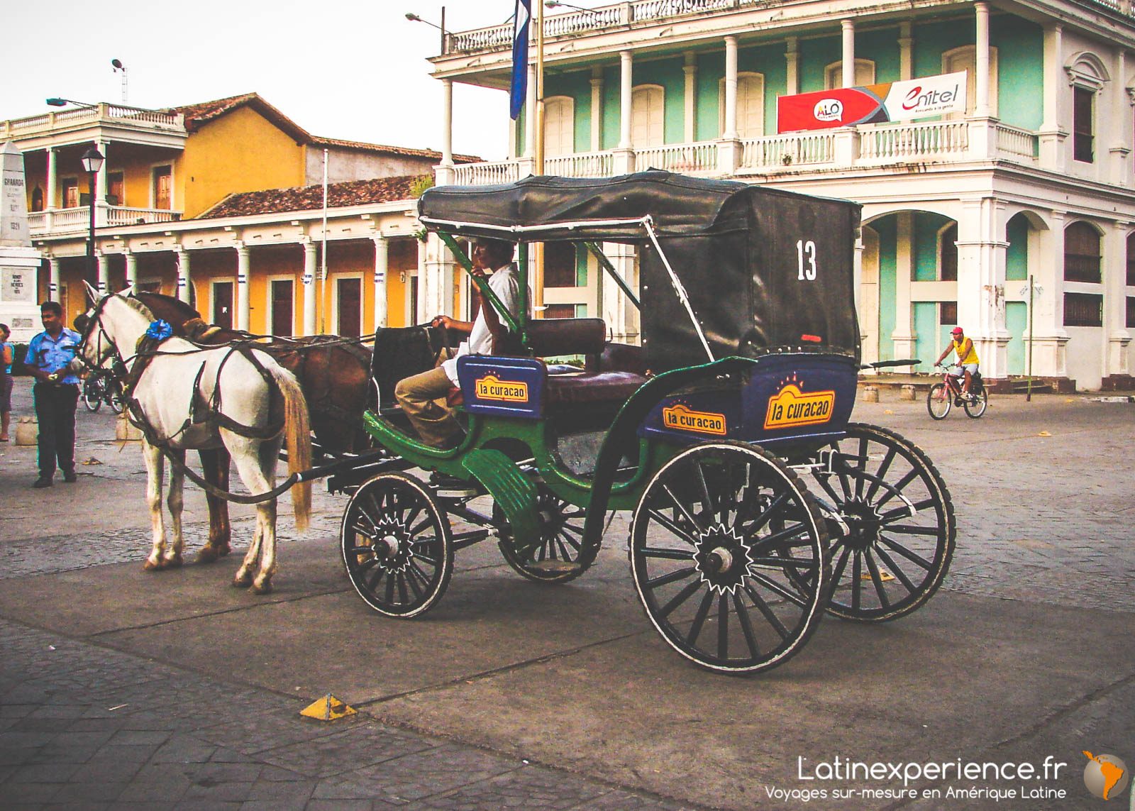 Calèche traditionnelle attelée à un cheval blanc devant des bâtiments coloniaux, Grenade, Nicaragua