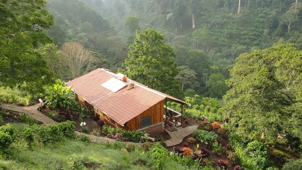 Cabane en bois à toit rouge avec panneaux solaires entourée de forêt tropicale, Bastilla, Nicaragua
