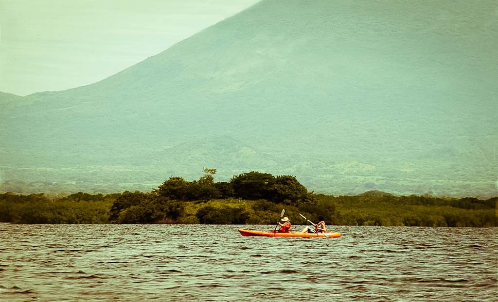 Kayak orange avec deux personnes pagayant sur le lac Nicaragua face au volcan Concepción, île d'Ometepe