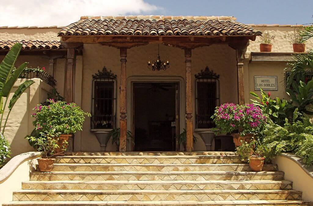 Entrée de l'Hôtel Los Robles avec colonnes en bois, escalier carrelé et bougainvilliers, Nicaragua