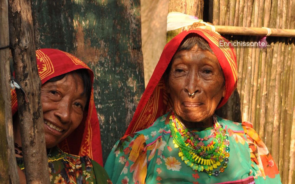 Deux femmes gunas en tenue traditionnelle colorée devant une case en bois, San Blas Panama