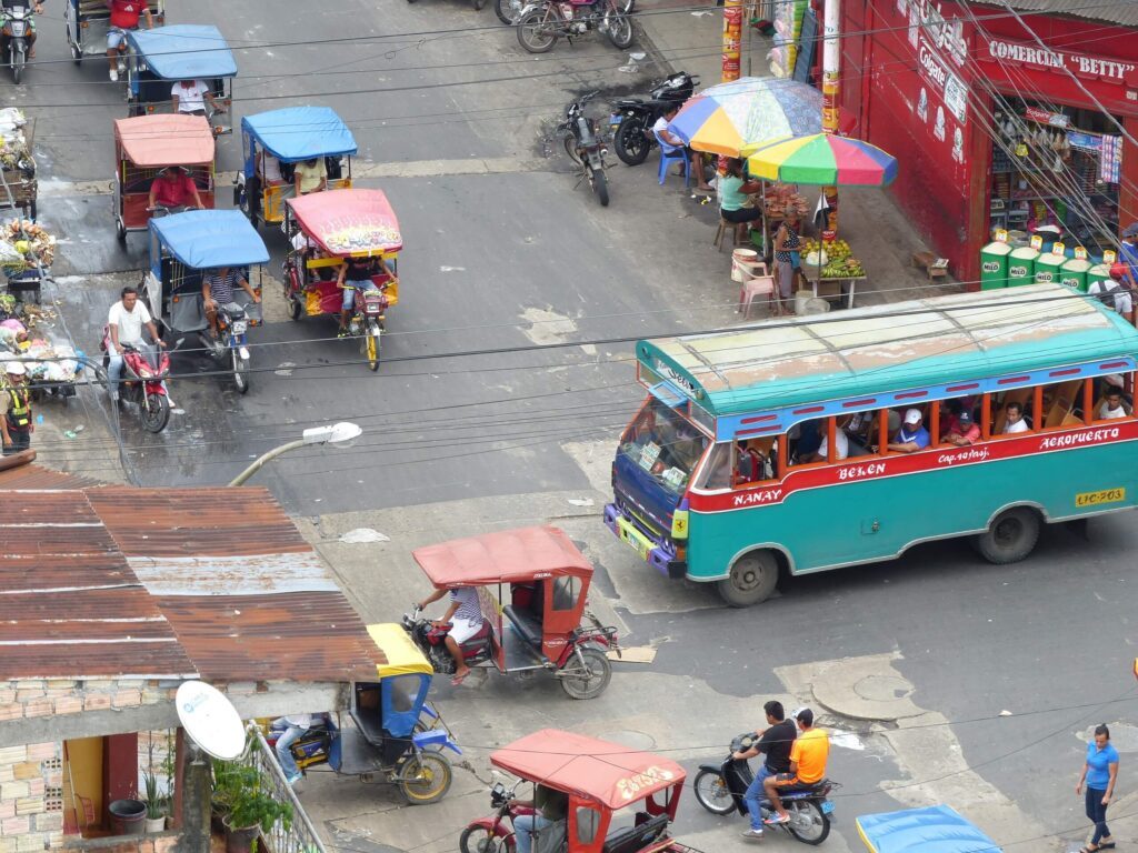 Vue aérienne d'une rue animée d'Iquitos avec tricycles motorisés, bus coloré et étals de marché, Pérou