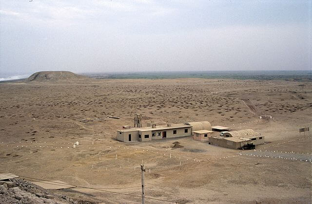 Vue aérienne d'un désert côtier avec bâtiments isolés et monticule, région de Chiclayo, Pérou