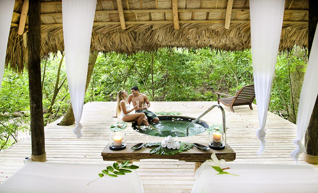 Couple dans un bain rond en bois sous une paillote entourée de végétation en République Dominicaine
