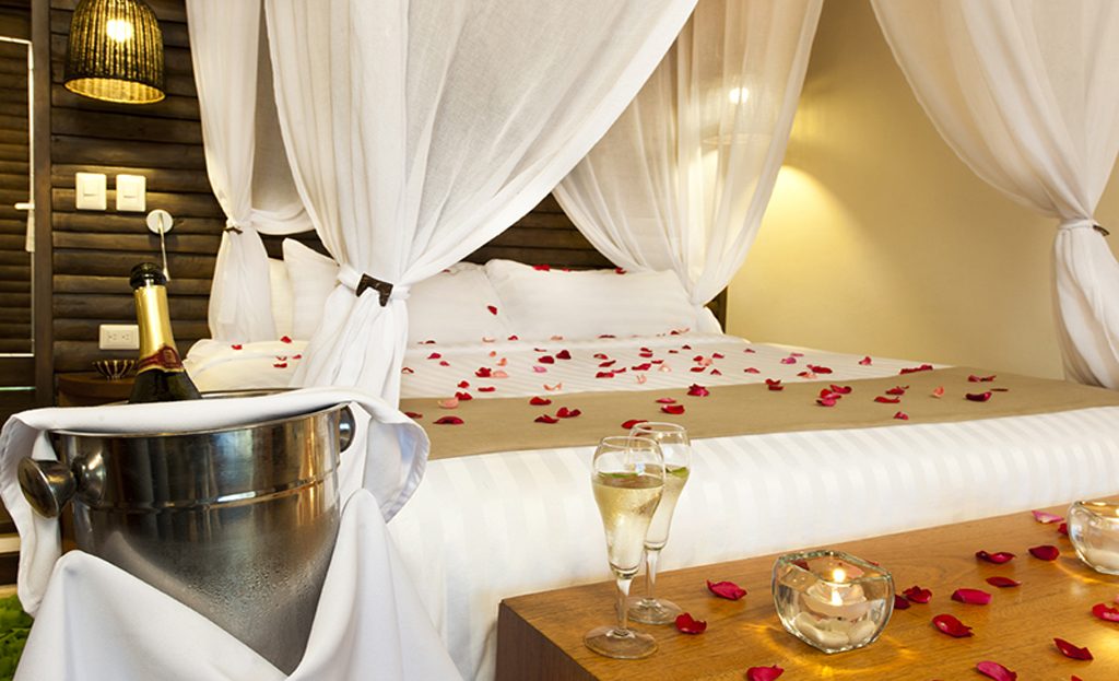 Chambre romantique avec lit à baldaquin, pétales de rose et champagne, République Dominicaine