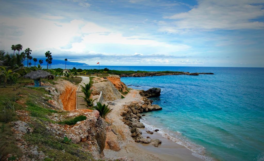 Côte rocheuse de Barahona avec sentier en bois, palmiers, cabane et mer turquoise, République Dominicaine
