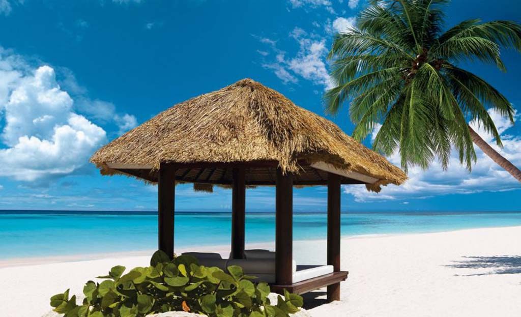 Paillote au toit de chaume avec lits de plage sur sable blanc à Cap Cana