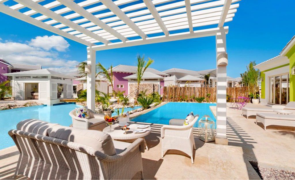 Terrasse avec pergola blanche, mobilier en osier et piscine dans un complexe à Cap Cana, République Dominicaine